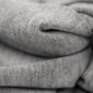 May include: Close-up of a gray, folded fabric with a textured surface. The fabric is soft and appears to be made of cotton.