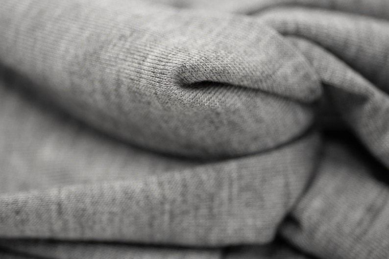 May include: Close-up of a gray, folded fabric with a textured surface. The fabric is soft and appears to be made of cotton.