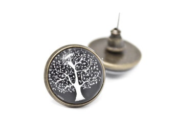 May include: A pair of bronze stud earrings with a black and white tree of life design.