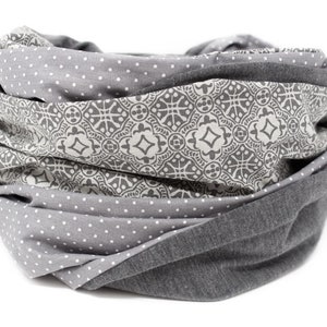 May include: Gray and white patterned infinity scarf with a geometric design. The scarf is made of soft fabric and is perfect for keeping warm in the winter.