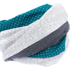 May include: A teal, gray, and white infinity scarf with a polka dot pattern and a floral design.