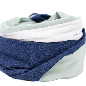 May include: A soft, multi-colored scarf with a floral pattern. The scarf is made of a stretchy fabric and is folded in a circle.