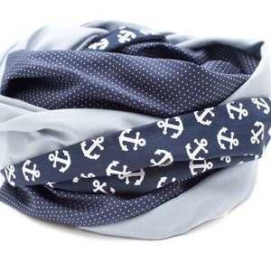 May include: A blue and gray scarf with a white anchor pattern. The scarf is folded and rolled into a circle.