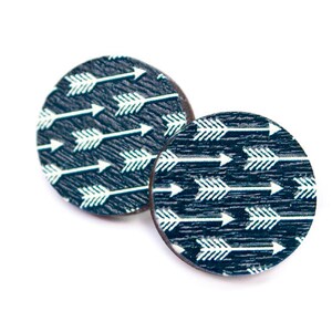 Könnte beinhalten: Zwei runde Holz-Untersetzer mit einem dunkelblauen Hintergrund und einem weißen Pfeilmuster.