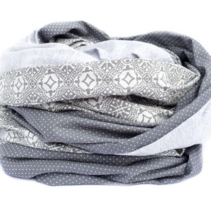 May include: A gray and white infinity scarf with a geometric pattern. The scarf is made of a soft, stretchy fabric and is perfect for keeping warm in the winter.