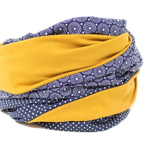 May include: A mustard yellow and navy blue fabric neck warmer with a white polka dot and white circle pattern.