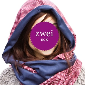 May include: A pink and white polka dot hooded scarf with a navy blue trim. The scarf is worn by a person whose face is covered by a purple circle with the text "zwei ECK" in white.