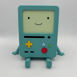 May include: A teal-colored BMO figurine from Adventure Time, featuring a screen with a smiling face, a yellow plus-shaped button, and a red button. The figurine has arms and legs, and is sitting upright.