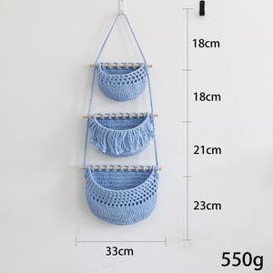 Puede incluir: Una cesta colgante de macram&eacute; azul claro de tres niveles con clavijas de madera. Las dos cestas superiores miden 18 cm de alto, y la cesta inferior mide 23 cm de alto. El ancho es de 33 cm. El peso total es de 550 g.