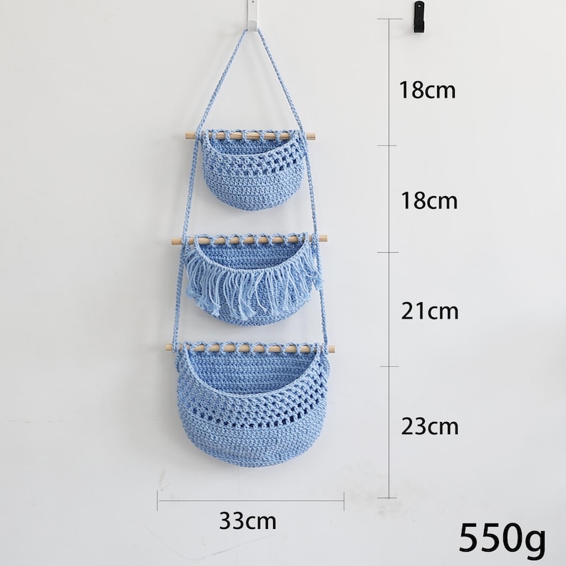 Puede incluir: Una cesta colgante de macram&eacute; azul claro de tres niveles con clavijas de madera. Las dos cestas superiores miden 18 cm de alto, y la cesta inferior mide 23 cm de alto. El ancho es de 33 cm. El peso total es de 550 g.