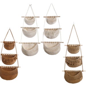 Puede incluir: Varias cestas colgantes de macram&eacute; en tonos beige y marr&oacute;n. Cada cesta est&aacute; suspendida por una cuerda y unida a una varilla de madera. Algunas cestas tienen flecos. Las cestas est&aacute;n dispuestas en conjuntos de tres.