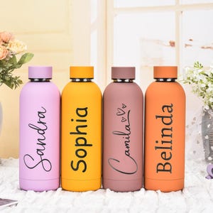 May include: Four colorful, personalized water bottles. Each bottle is a different color: lavender, yellow, mauve, and orange. Each bottle has a name printed in black script: Sandra, Sophia, Camila, and Belinda. The bottles have matching colored lids.