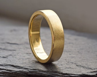 May include: A simple gold wedding band with a brushed finish.