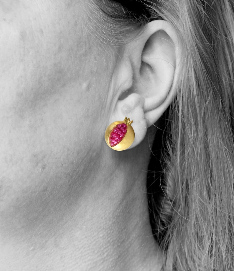 May include: A pair of gold earrings shaped like pomegranates with red ruby stones.