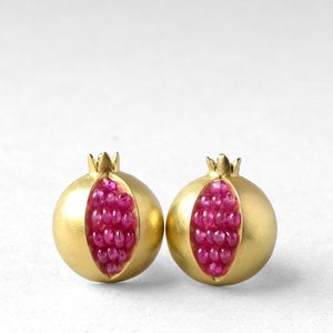 May include: A pair of gold earrings shaped like pomegranates, each with a red ruby gemstone centre.