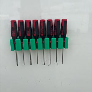 May include: A set of eight black and red handled ICON tools, including picks and a scraper, displayed in a green holder. The tools are arranged in a row, with the ICON logo visible on each handle.