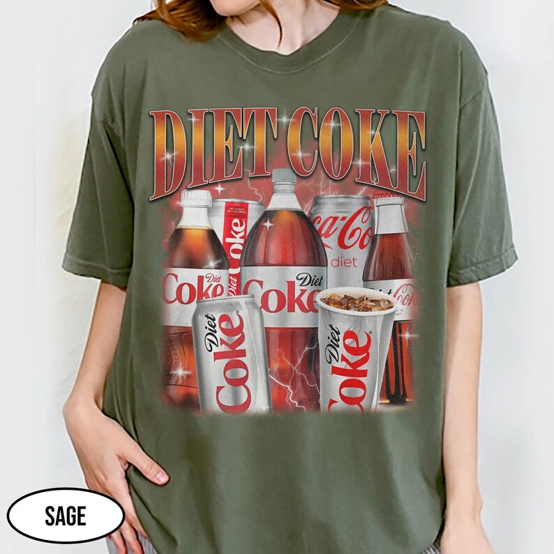K&ouml;nnte beinhalten: Salbeigr&uuml;nes T-Shirt mit einem Diet Coke-Motiv. Das Design zeigt verschiedene Diet Coke-Produkte, wie Flaschen, Dosen und einen Becher, mit dem Schriftzug "Diet Coke" in einer Retro-Schriftart. Das T-Shirt hat einen l&auml;ssigen Stil.