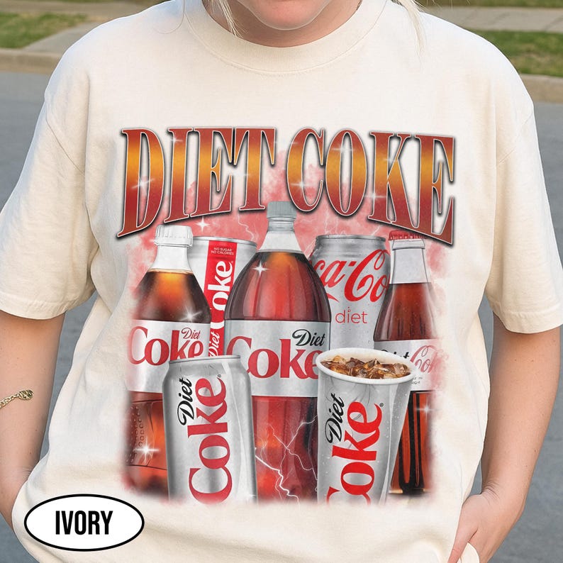 K&ouml;nnte beinhalten: Cremefarbenes T-Shirt mit einem Diet Coke-Motiv. Das Design zeigt verschiedene Diet Coke-Flaschen, Dosen und einen Becher, mit dem Wortlaut "DIET COKE" in fetter, roter und goldener Schrift. Das T-Shirt hat einen Vintage-Look.