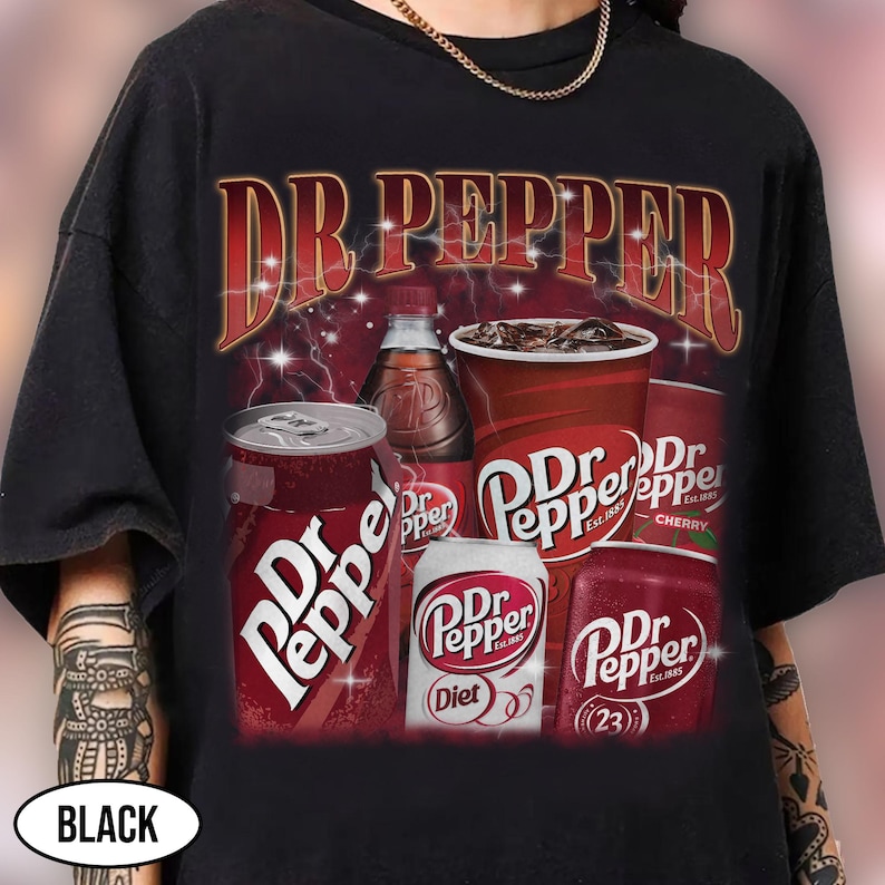 May include: Black t-shirt featuring a Dr Pepper graphic. The design includes various Dr Pepper products: cans, a bottle, and a cup, with the brand name in a vintage style. The shirt has a classic, retro aesthetic.