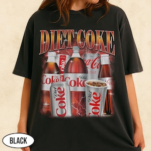 K&ouml;nnte beinhalten: Schwarzes T-Shirt mit einem Diet Coke-Design. Der Aufdruck zeigt Diet Coke-Flaschen, Dosen und einen Becher, mit dem Schriftzug "DIET COKE" in einem Retro-Stil. Das T-Shirt ist dunkel.