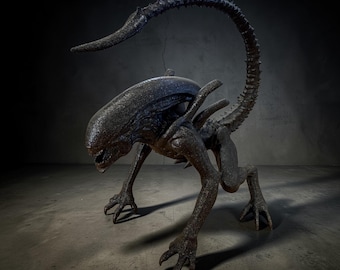 May include: A detailed sculpture of an Alien creature, featuring a dark, textured surface. The creature is posed on all fours with a long, curved tail and a distinctive head shape. The sculpture is set against a dark, textured background.