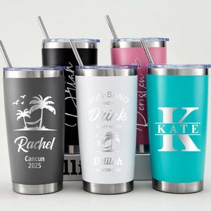 May include: Five stainless steel travel tumblers with lids and straws. The tumblers are in various colors: gray, black, white, pink, and teal. Each tumbler has a unique design, including names, initials, and tropical graphics. The tumblers are designed for cold beverages.