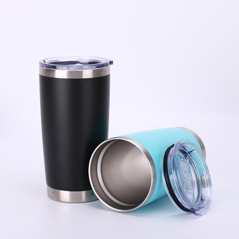 May include: Two stainless steel insulated tumblers. One is black, upright, with a clear lid. The other is light blue, lying on its side, with a clear lid off to the side. Both tumblers have a silver rim at the top and bottom.