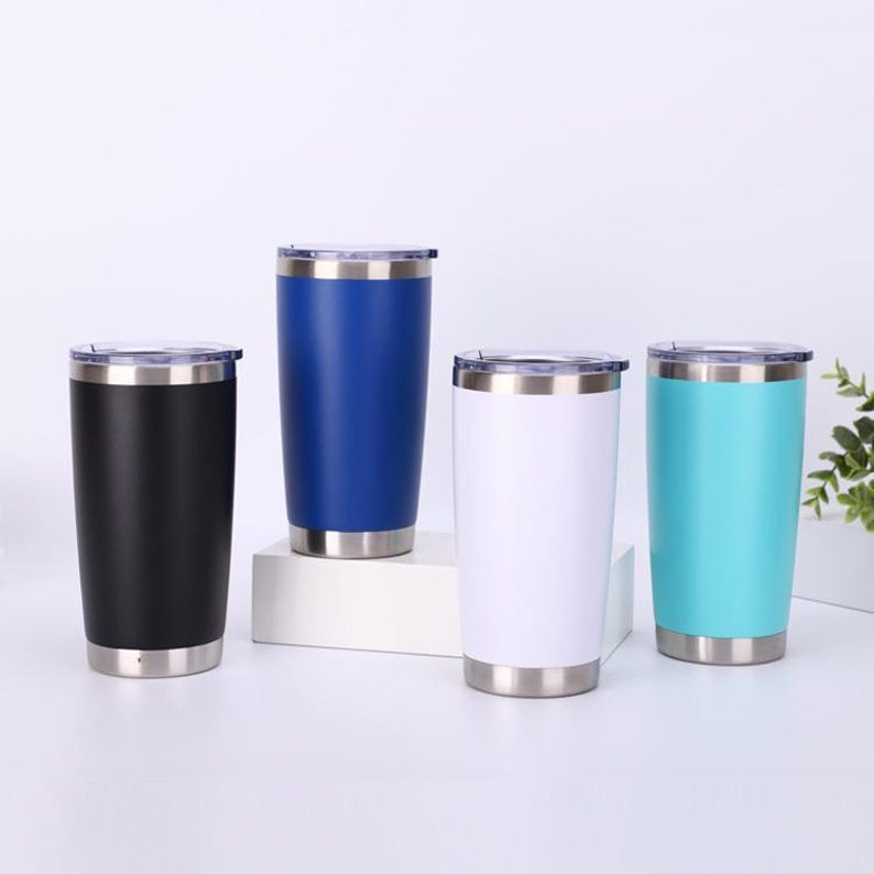 May include: Four stainless steel insulated tumblers in black, blue, white, and teal. Each tumbler has a silver rim and base, and a clear lid. The tumblers are cylindrical and appear to be empty.