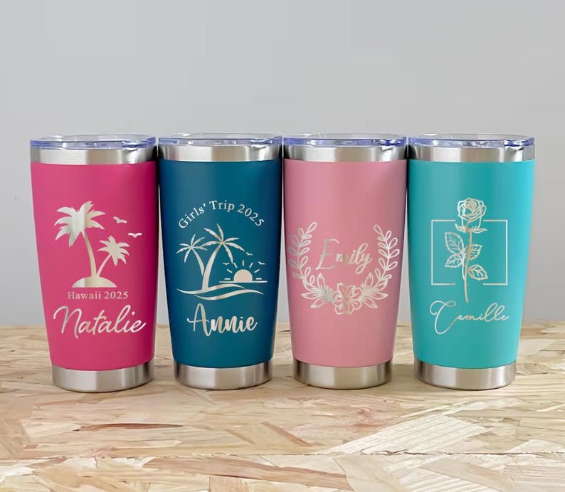 May include: Four stainless steel tumblers in pink, teal, and blue. Each tumbler features a unique design and name, including a palm tree, a rose, and floral accents. The text includes "Hawaii 2025", "Girls' Trip 2025", and names.