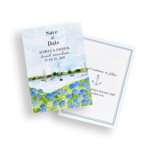 Op de afbeelding: Waterverf save-the-date kaarten met een kustlandschap, zeilboten, blauwe hortensia's en de tekst "Save the Date". De kaart bevat namen, locatie en datum.