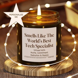Peut inclure: Une bougie allumée dans un pot en verre ambré avec une étiquette blanche portant l'inscription Smells Like The World's Best Tech Specialist, Infused With Hustle, Commitment, Dedication & Passion, Eco-Friendly And Non-Toxic, Hand-Poured In The USA.