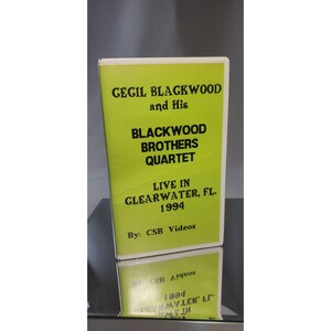 Pode incluir: Uma capa de CD verde e branca com o texto "CECIL BLACKWOOD and His BLACKWOOD BROTHERS QUARTET LIVE IN CLEARWATER, FL. 1994 By: CSB Videos". A capa é refletida na superfície abaixo.