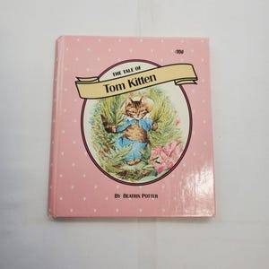 Peut inclure: Un livre pour enfants vintage intitulé "The Tale of Tom Kitten" de Beatrix Potter. La couverture rose à pois blancs présente une illustration d'un chat en tenue bleue. Le titre est inscrit dans une bannière.