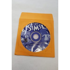 May include: A computer game disc for "The Sims" in an orange envelope. The disc is blue with the game's logo and images of people. Text on the disc reads "The People Simulator from the Creator of Sim City."