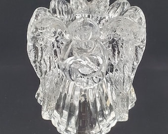 May include: Clear glass angel figurine with detailed wings and a halo. The angel is holding a sphere, and the design is intricately carved. The figurine is a decorative item, likely for display or as a collectible.