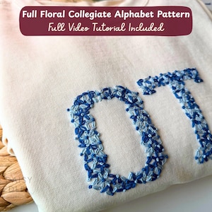 Puede incluir: Una sudadera de color crema con las letras OT bordadas en un patrón floral azul. El texto Full Floral Collegiate Alphabet Pattern Full Video Tutorial Included es visible en la parte superior de la imagen.