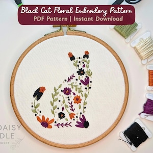Puede incluir: Un bastidor de bordado de madera con tela blanca que muestra una silueta de gato negro bordada con motivos florales coloridos. El texto Black Cat Floral Embroidery Pattern PDF Pattern | Instant Download aparece arriba. Cinco carretes de hilo están dispuestos a la derecha.