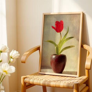 May include: A framed print of a red tulip in a dark red vase. The tulip has green leaves and is set against a soft, neutral background. The print is displayed on a wooden chair with a woven seat.