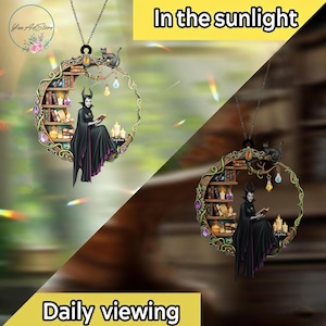 May include: A circular pendant featuring a fantasy scene with a woman in a black cloak reading a book, surrounded by a bookshelf, candles, and a black cat. The pendant is suspended from a silver chain. Text on the image reads "In the sunlight" and "Daily viewing."