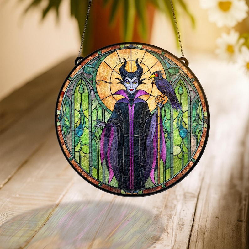 Pu&ograve; includere: Vetrata rotonda raffigurante un personaggio con corna nere, una veste viola e nera e un corvo. La finestra ha una cornice in metallo nero e una catena per appenderla. Lo sfondo &egrave; un mix di verde, giallo e arancione.