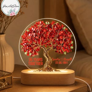 May include: A circular acrylic light featuring a wire-wrapped tree with red crystal leaves. The base is light-colored wood. Text on the acrylic reads 35 YEARS TOGETHER, Sandra & Russell, and 22.06.1991 in red lettering. The tree is illuminated from below.