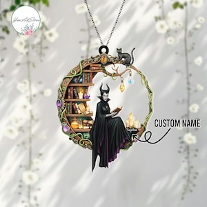 May include: A black Maleficent-themed pendant necklace. The pendant features Maleficent reading a book, a black cat, a bookshelf, and candles. The pendant is surrounded by a crescent-shaped frame with vines and gemstones. The text "CUSTOM NAME" is also visible.