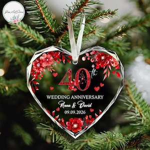 May include: A heart-shaped clear acrylic ornament featuring a red floral design with the text 40th WEDDING ANNIVERSARY, the names Anna & David, and the date 09.09.2026. The ornament is suspended by a white ribbon and has a faceted edge design.