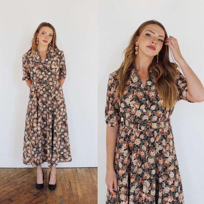 K&ouml;nnte beinhalten: Ein mittellanges Kleid mit einem Blumendruck in Braun-, Beige- und Wei&szlig;t&ouml;nen. Das Kleid hat einen Kragen, kurze &Auml;rmel und einen Knopfleisten vorne. Es hat einen G&uuml;rtel in der Taille.