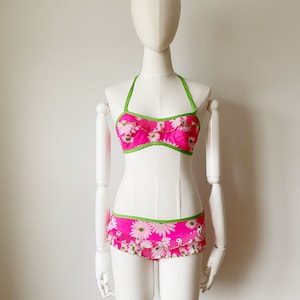 May include: A pink and green floral print bikini with a halter top and ruffled bottom.