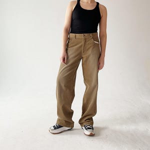 May include: A pair of brown corduroy pants with a wide leg silhouette. The pants have a high waist and a relaxed fit.