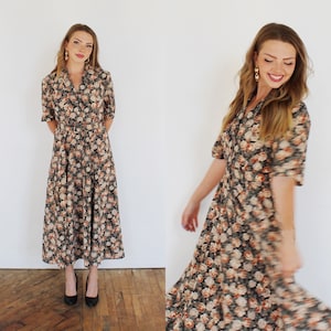 K&ouml;nnte beinhalten: Ein lang&auml;rmeliges Blumenkleid mit Knopfleiste und Kragen. Das Kleid hat einen dunklen Hintergrund mit einem Blumenmuster in Orange-, Braun- und Wei&szlig;t&ouml;nen.