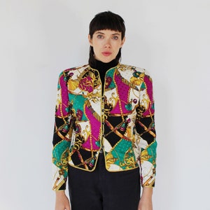 May include: A white, black, green, pink and gold patterned jacket with a mock neck and button closure.