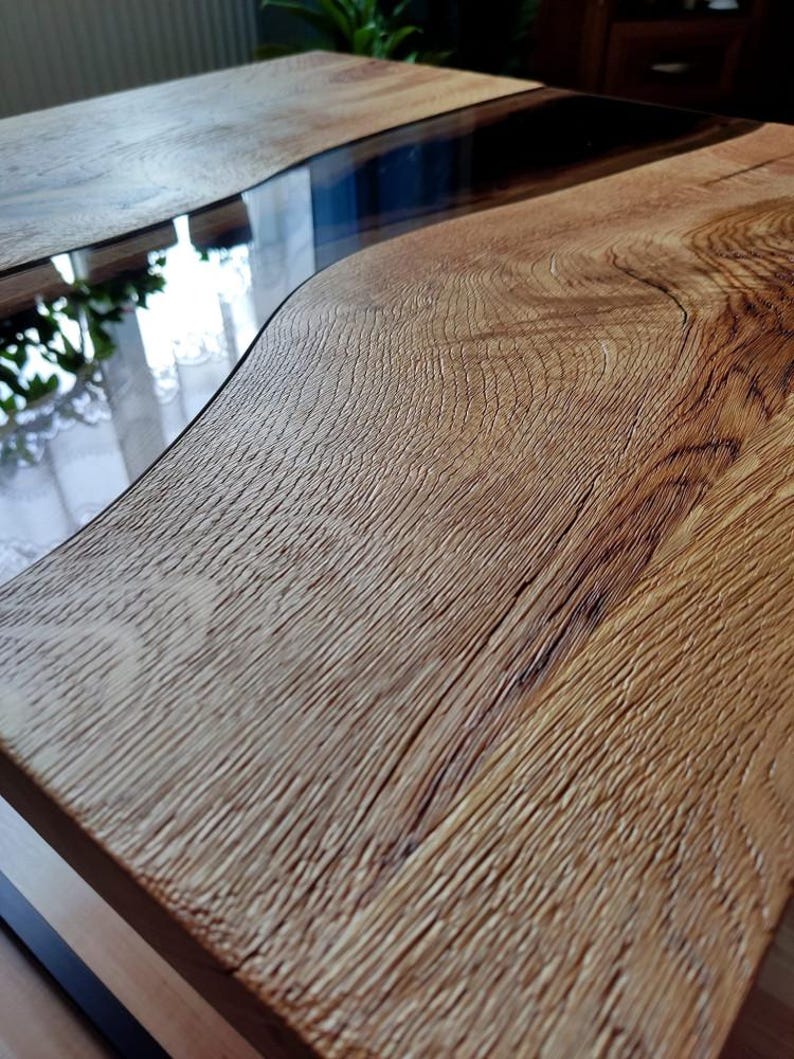 May include: A wooden coffee table with a natural wood finish and a clear epoxy resin river flowing through the center.