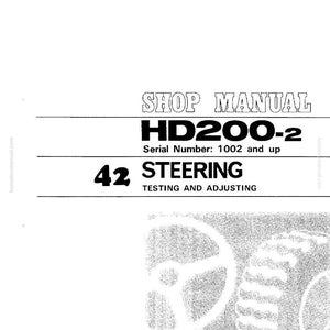 Puede incluir: Portada del manual de taller con el texto "SHOP MANUAL HD200-2 N&uacute;mero de serie: 1002 y superior 42 STEERING TESTING AND ADJUSTING". La imagen tambi&eacute;n incluye un volante y un neum&aacute;tico.